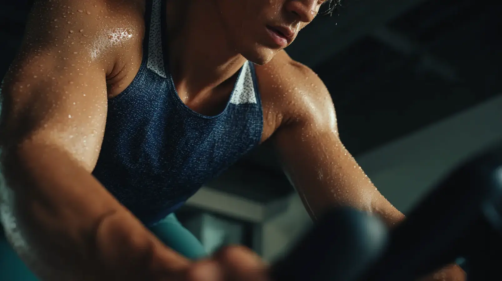 Primo piano di un atleta sudato dopo un intenso allenamento cardio su una cyclette, che mostra lo sforzo e la determinazione.